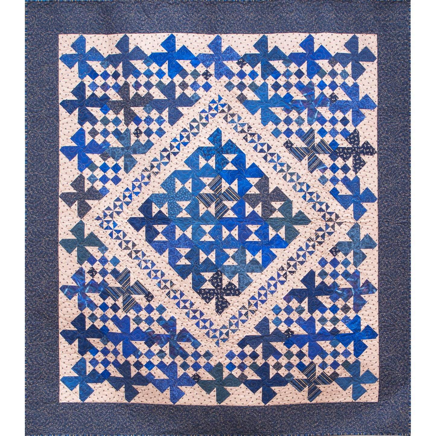 Fun pin-wheel like blocks in shades of blue quilt with an inner design with small border or similar pinwheel blocks and outer includes checker borders between blocks.