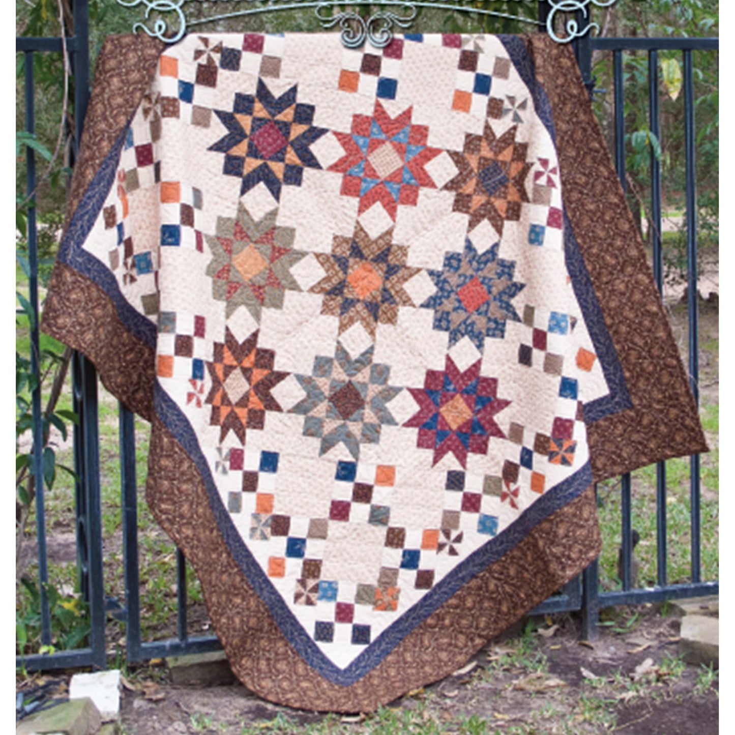 Quilt with star pattern draped over a metal gate