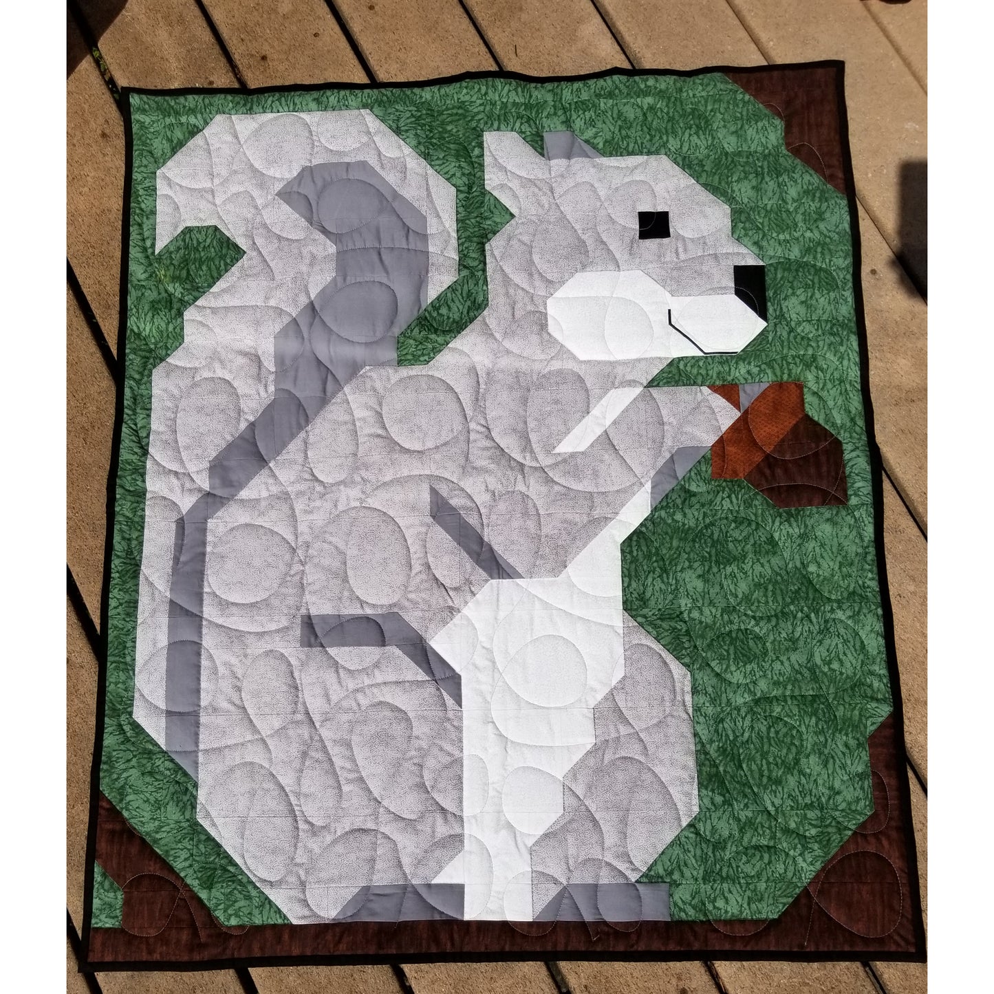 Adorable squirrel holding a nut quilt showing completed quilt.