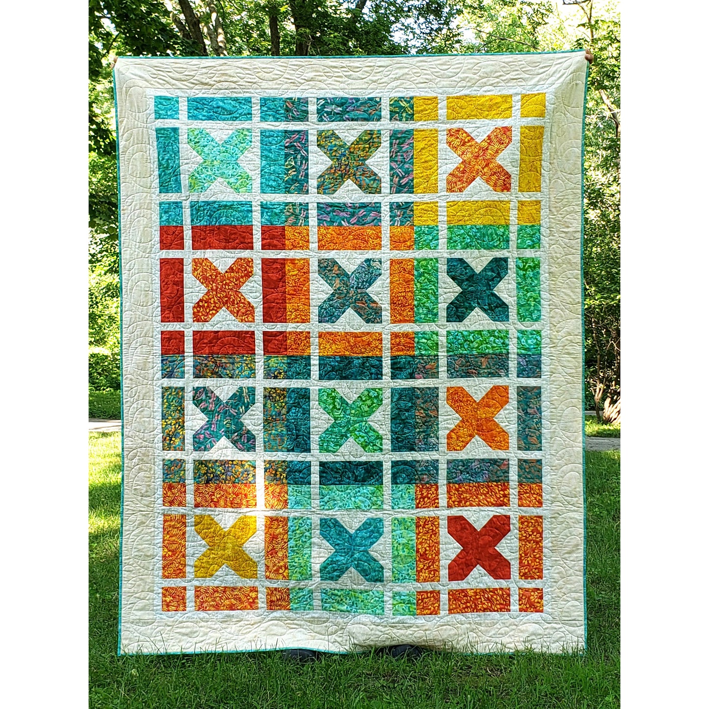 Bright and fun Kisses quilt features blocks of X's which represent Kisses. Each block is a bright color with white background inside with a bight colored X.