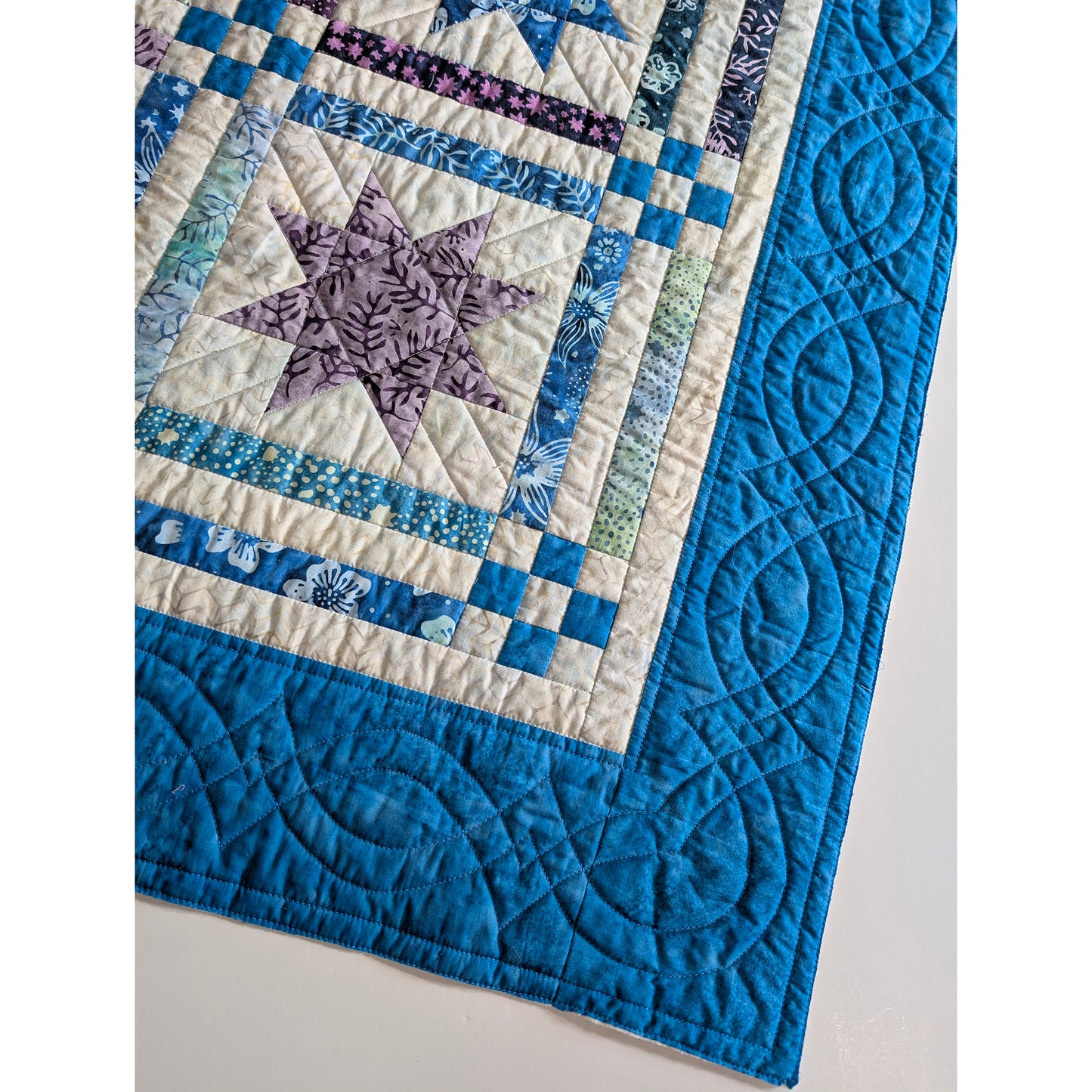 Quilt with blue and purple star design on a white background
