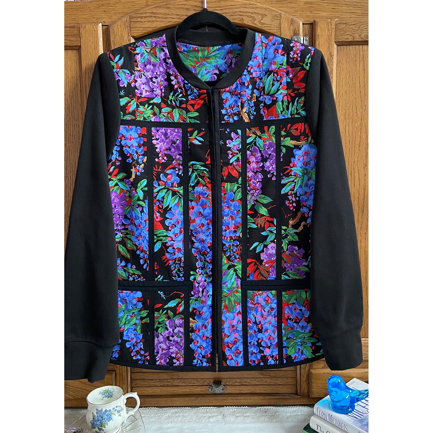 Beautiful jacket with lovely flower fabric in the middle with piping in a few places and pockets on either side of the zipper. Solid black sleeves.