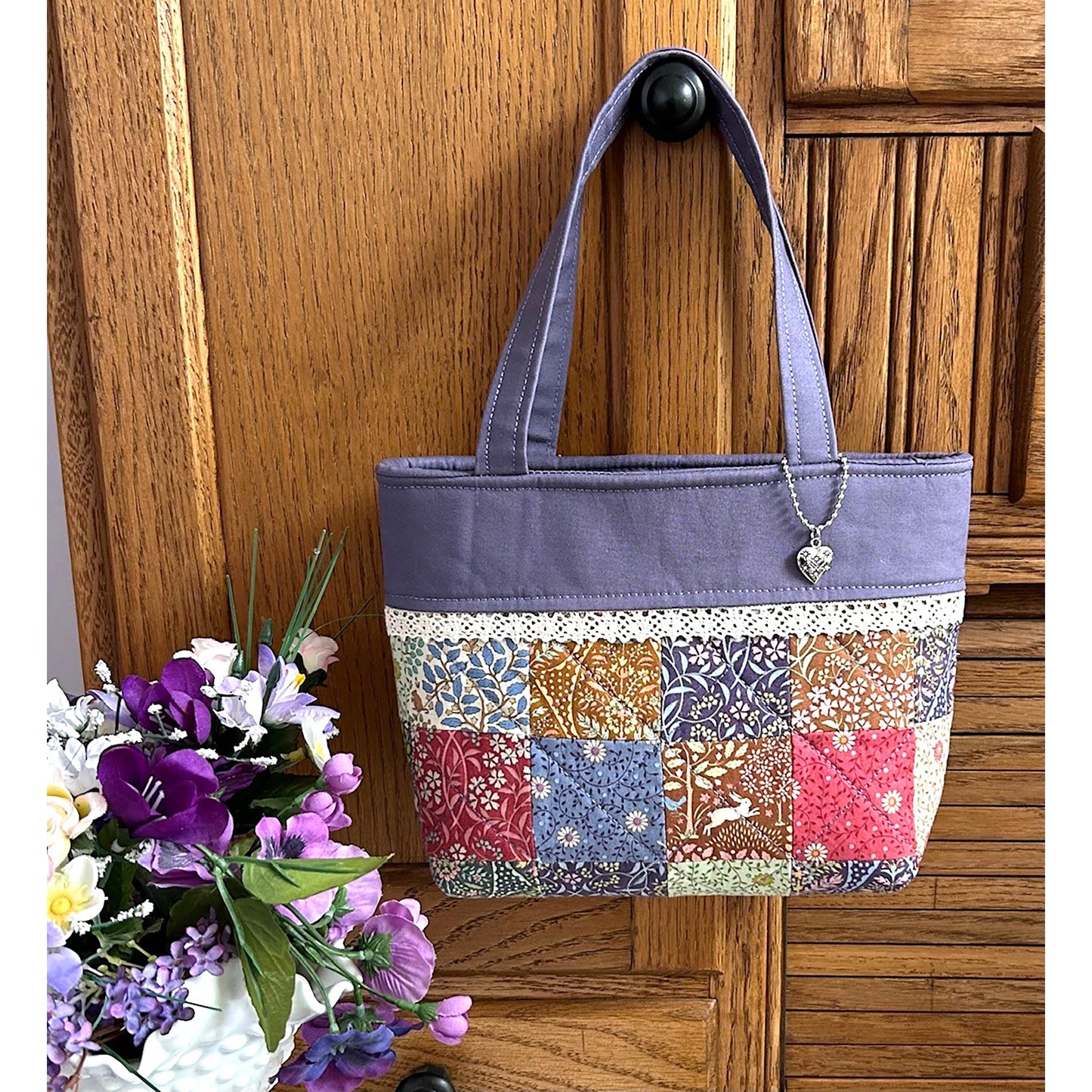 This is the cutest little tote bag using a mini charm pack! Shown with purple fabric top and multiple colored floral charms fabric.