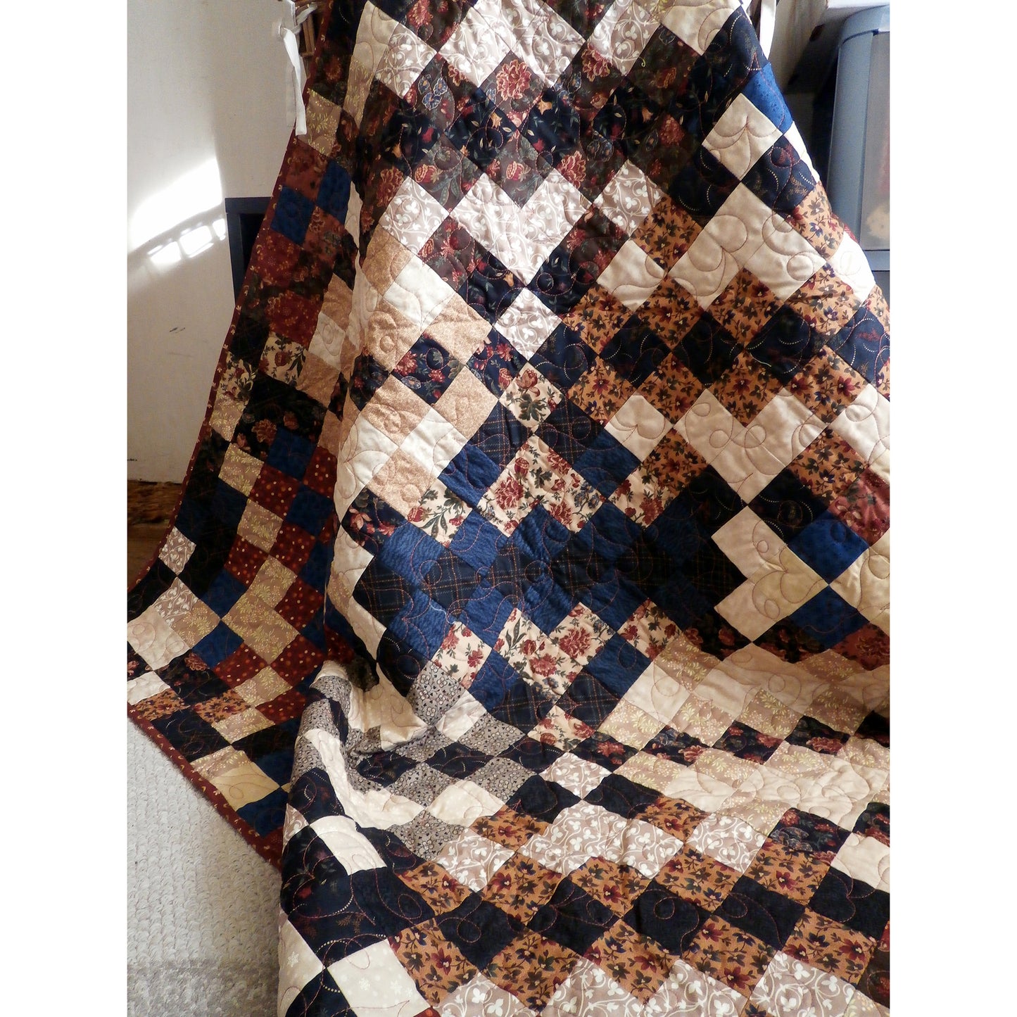 A fun quilt featuring an array of cream, brown, and blue squares arranged in a patchwork design