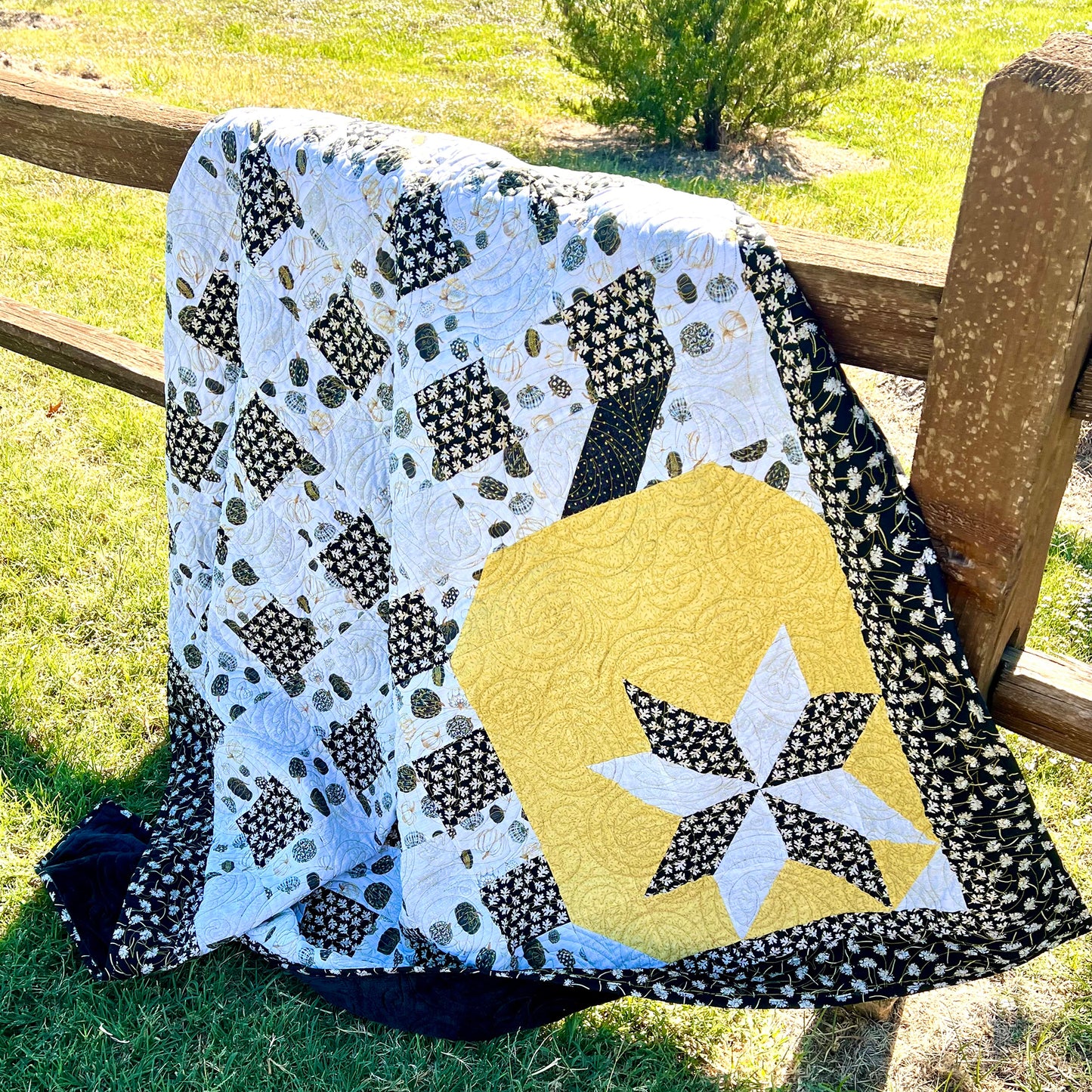 Floral squares print quilt with a yellow pumpkin or apple in the bottom corner with white and floral star on it.