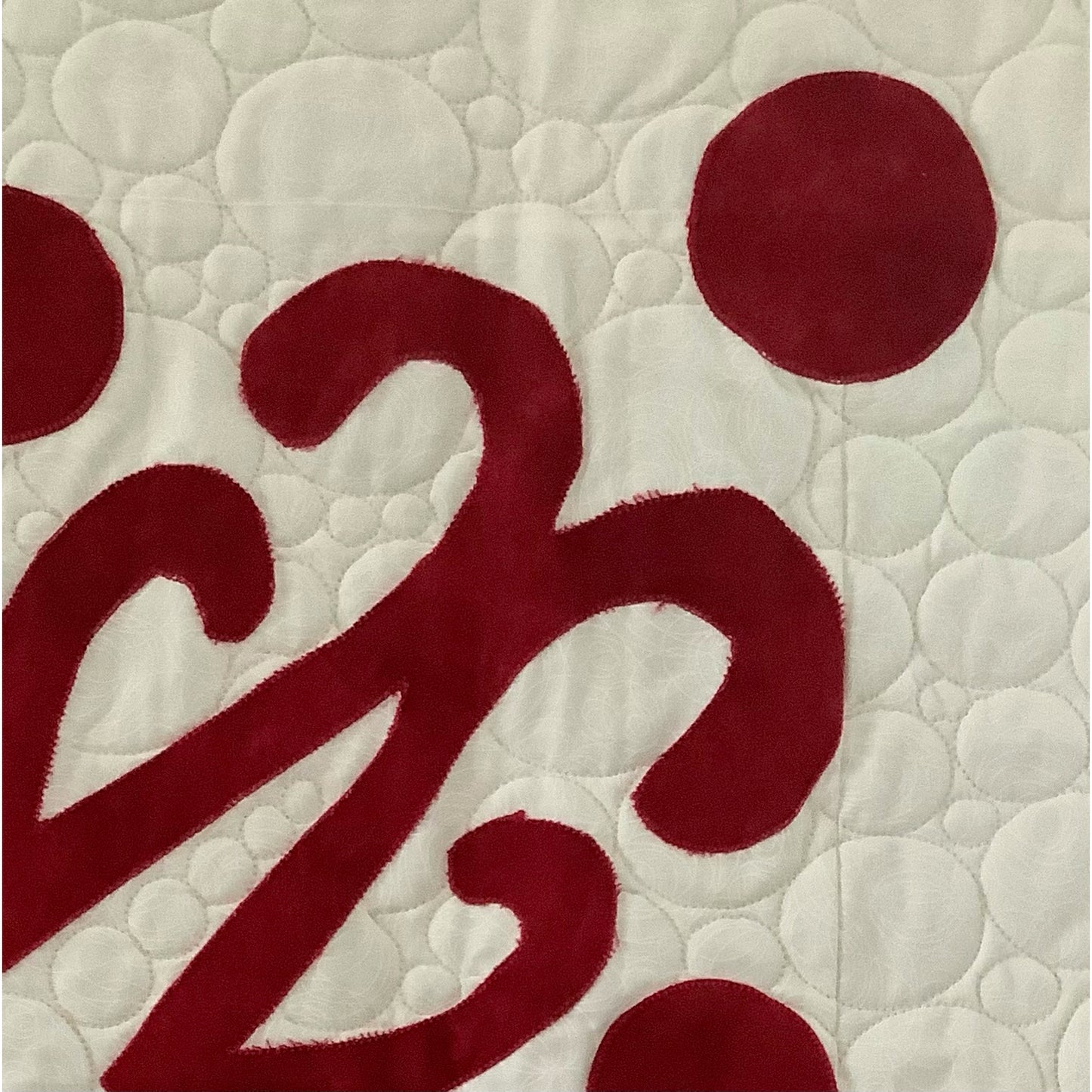 Close up image of one side of design of applique on white background.