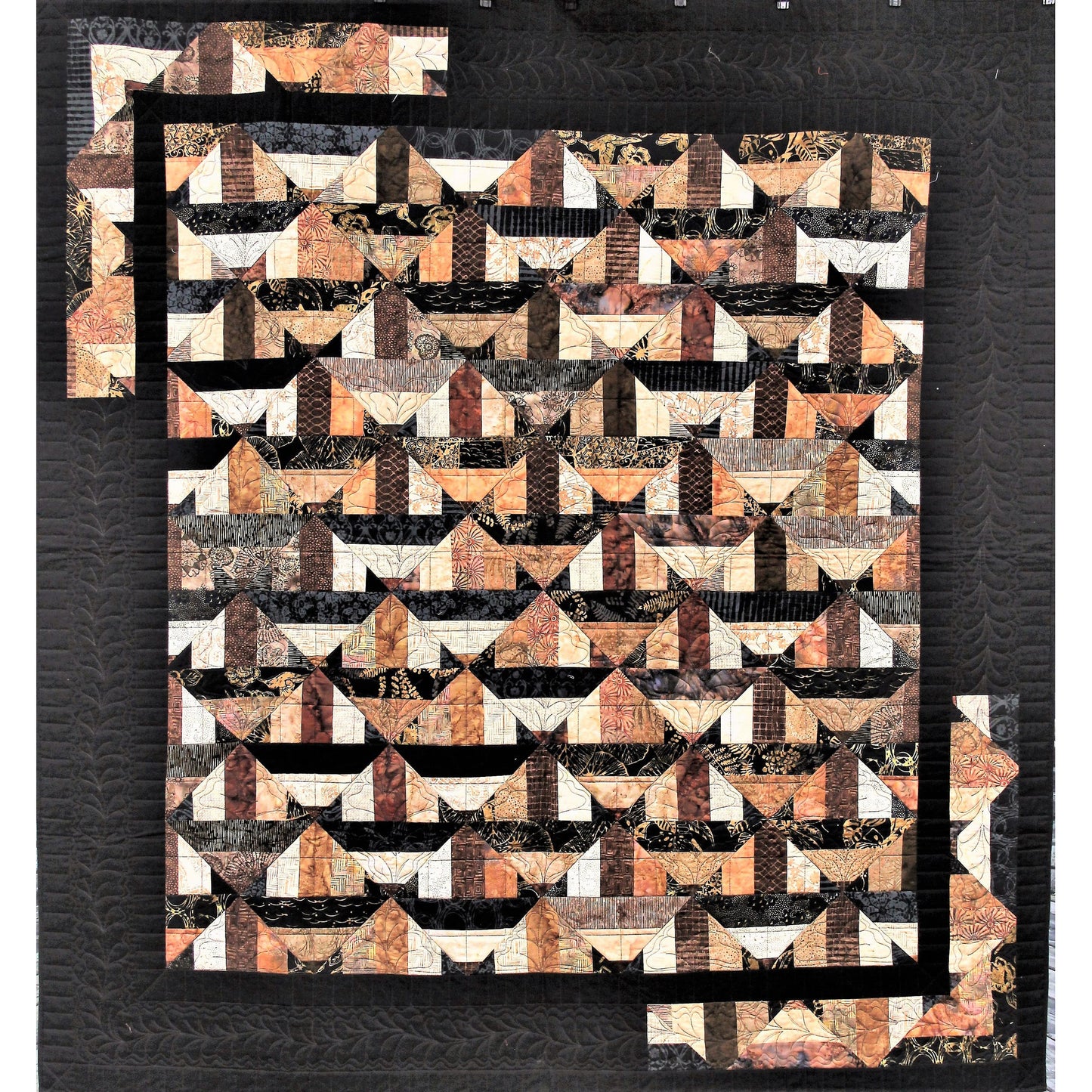 Geometric patterned quilt with brown, black, and white colors on a dark background
