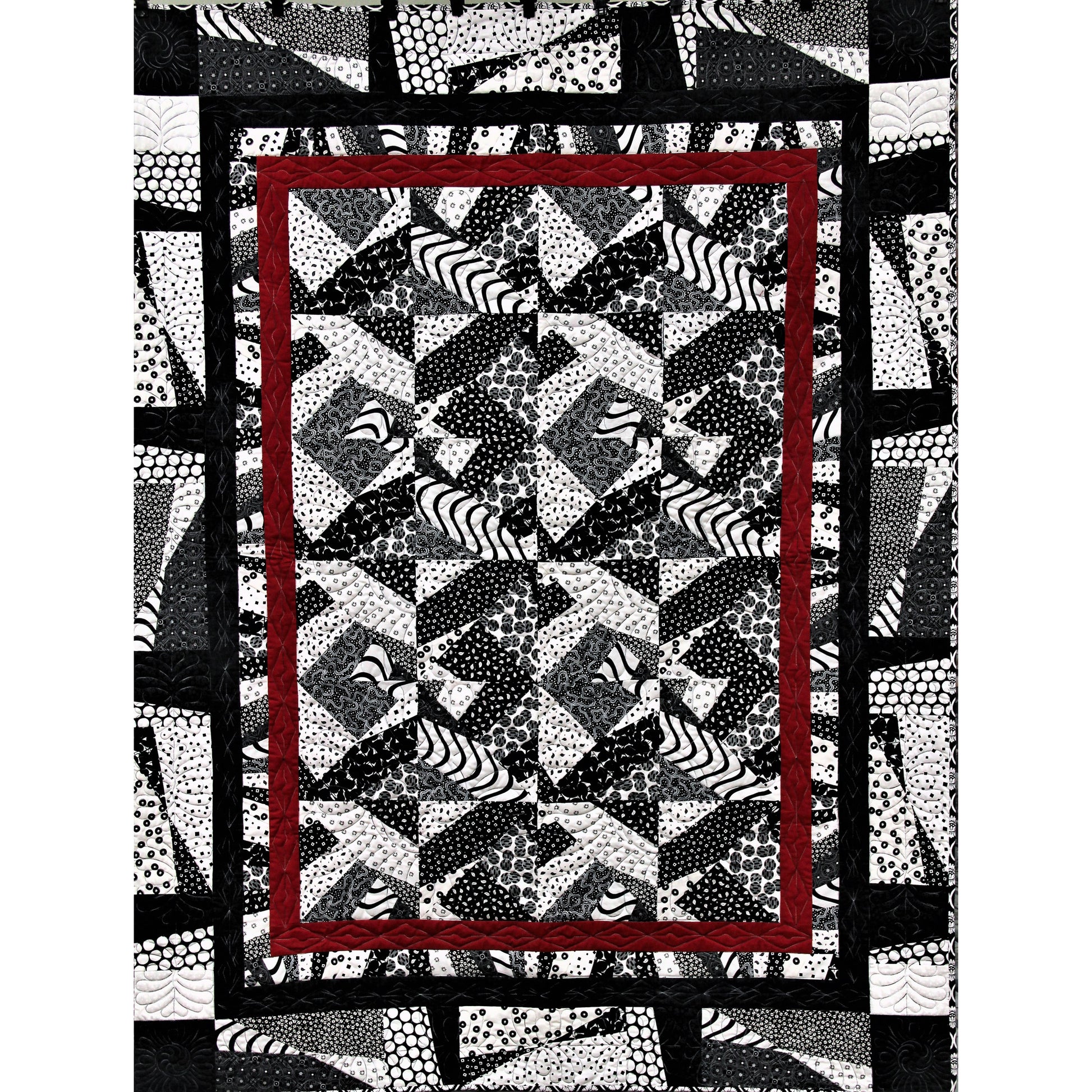 Quilt with geometric pattern and red border on a white background