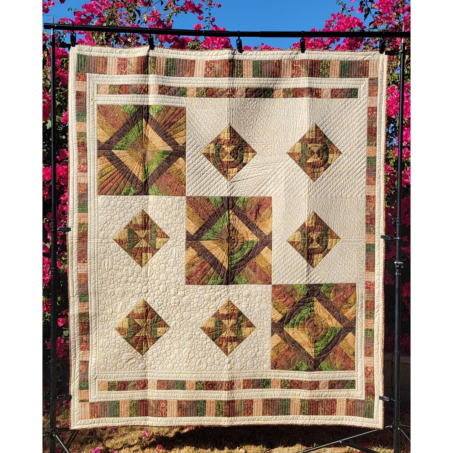 Quilt with geometric pattern displayed outdoors against a floral background