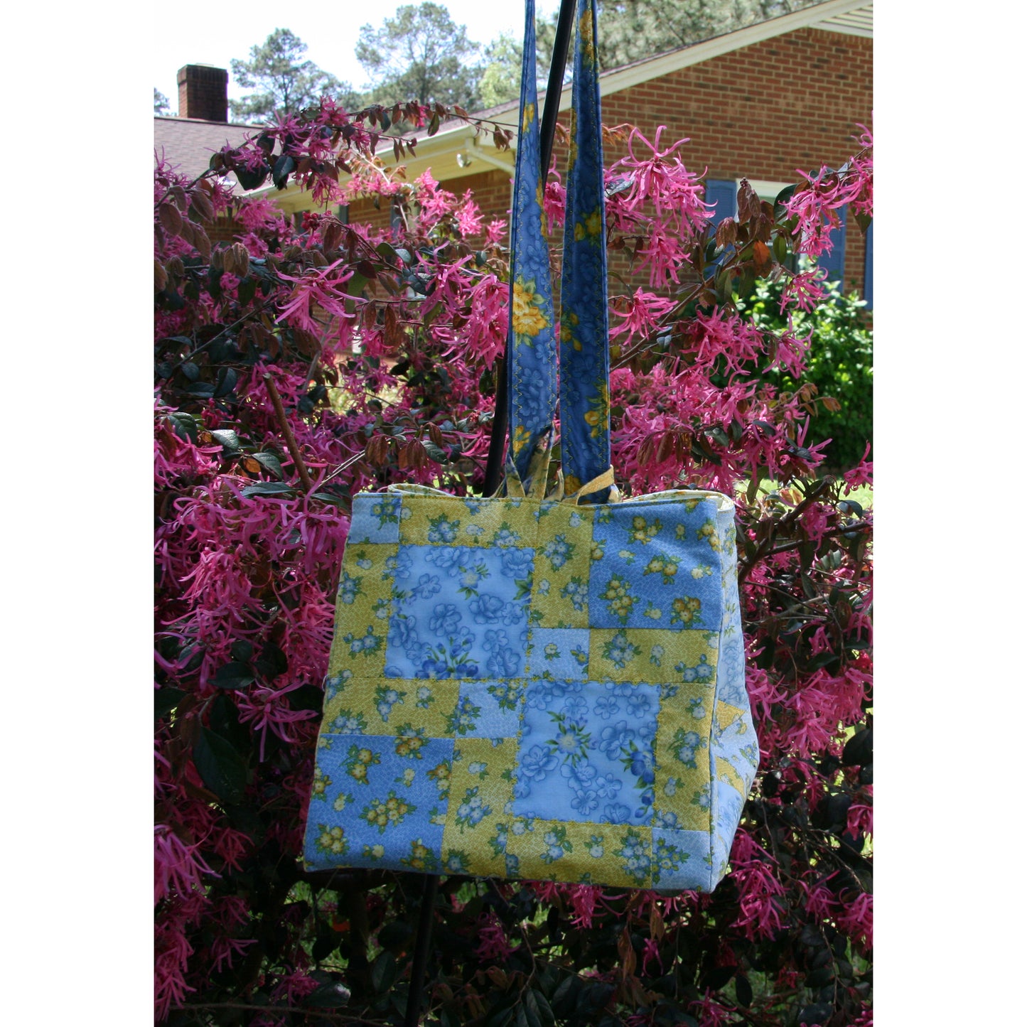 Floral patterned bag hanging on a pink flowering bush