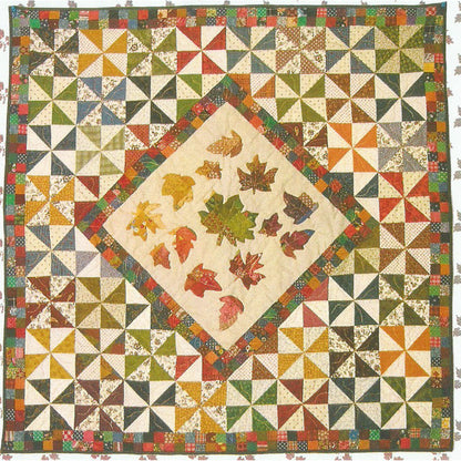 Beautiful fall quilt features colorful pinwheels and a diamond in the middle with colorful falling leaves.