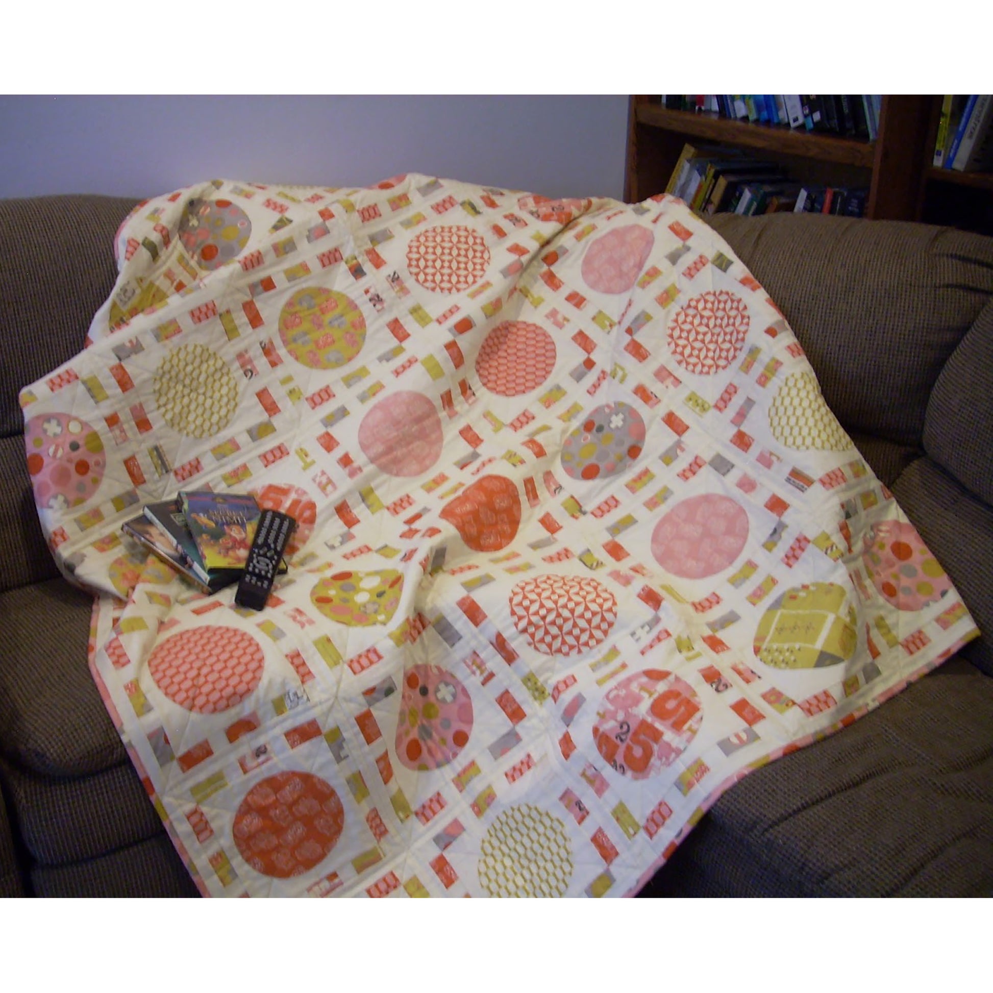 Fun quilt features blocks of colorful circles, like pizza, surrounded by thin colorful fabric, like tickets.  Fun movie watching quilt.  Shown draped on a couch with some movie DVDs.