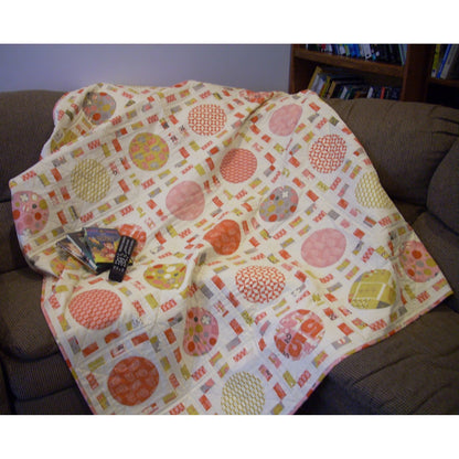 Fun quilt features blocks of colorful circles, like pizza, surrounded by thin colorful fabric, like tickets.  Fun movie watching quilt.  Shown draped on a couch with some movie DVDs.