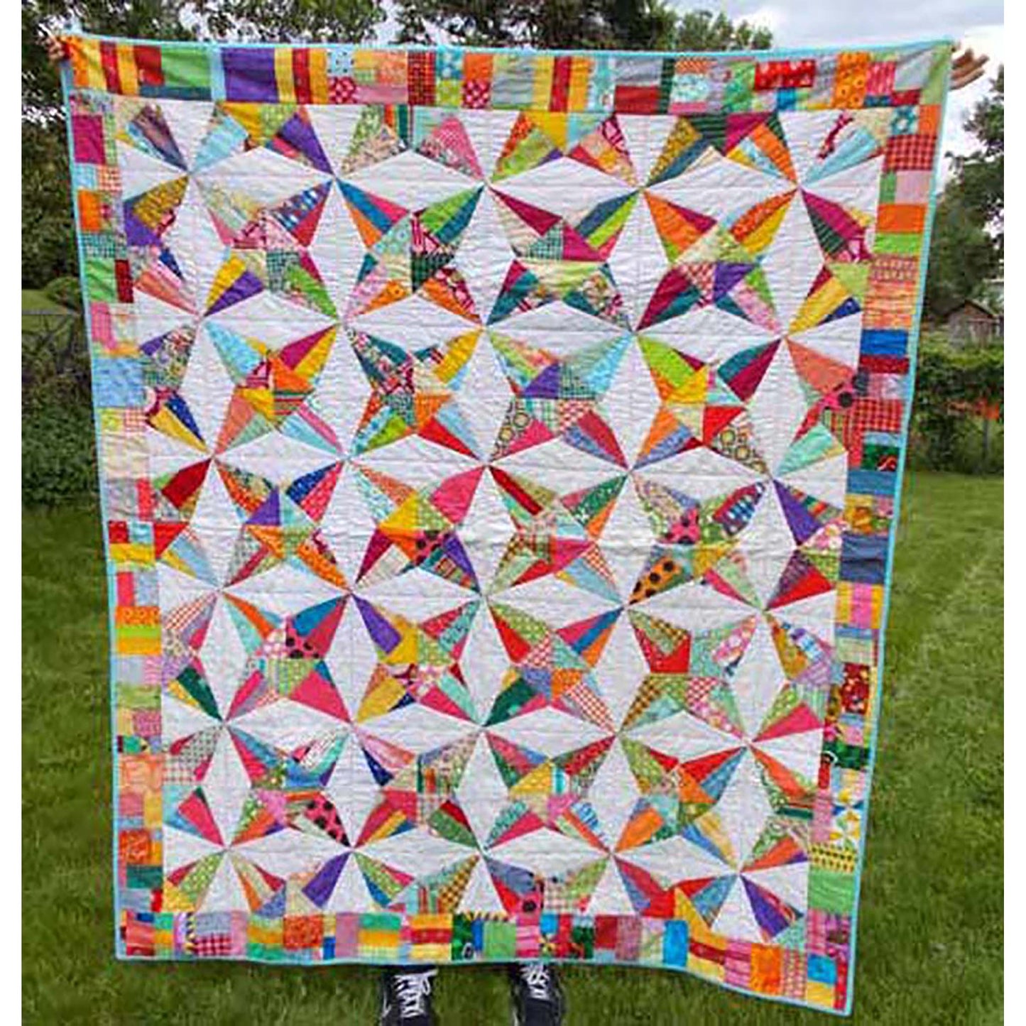 Kaleidoscope quilt is a fun quilt of stars in multiple fabrics with a cream background. Even the border is scrappy.