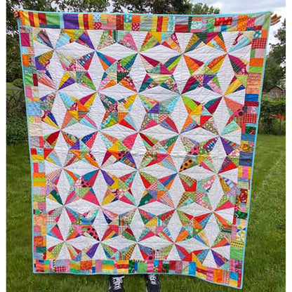 Kaleidoscope quilt is a fun quilt of stars in multiple fabrics with a cream background. Even the border is scrappy.
