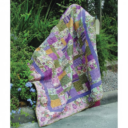 Pretty floral quilt shown draped in a garden.