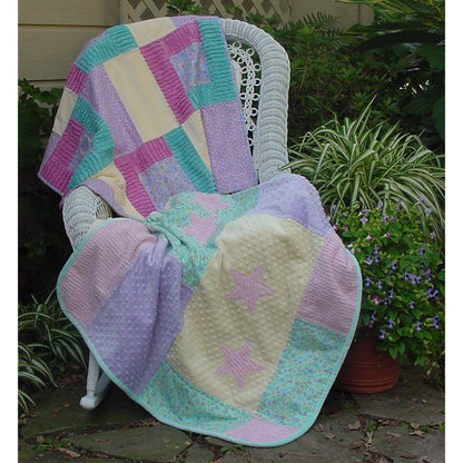 Two baby quilts draped over a chair.  Top quilt features squares of bright colors.  Bottom quilt features pastel blocks with pink stars.