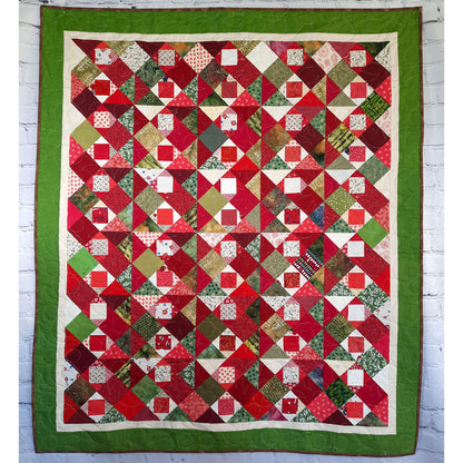 Fun scrappy quilt features Christmas colored fabric in a patchwork of squares.