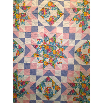 Hug Life quilt features two blocks one star and one diamonds inside each other. This version has bright bear fabric and complimenting pink, purple, and white solid fabric.  Showing a closeup of the star so you can see how the focus fabric can shine.