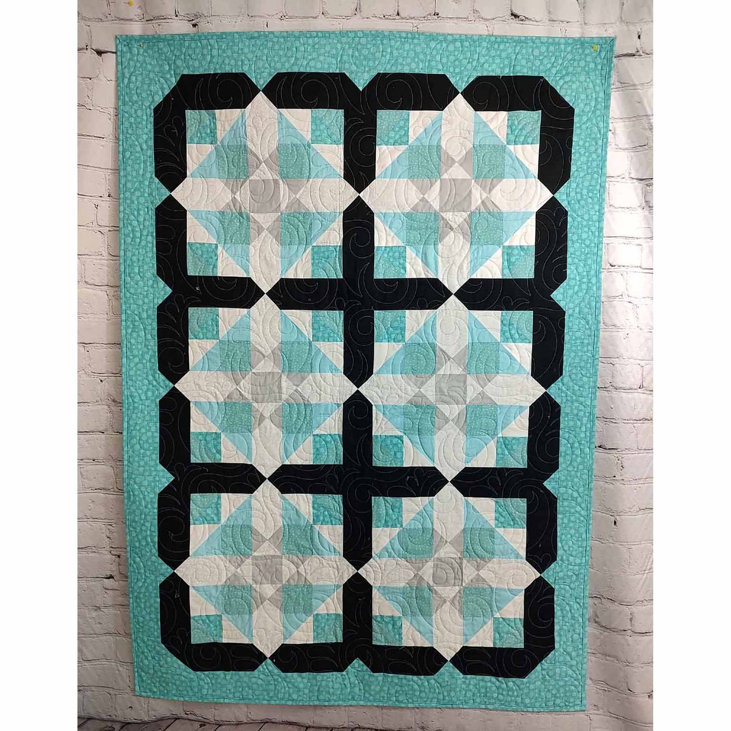 Unique quilt features blocks of diamonds with subtle flowers inside with black outline of each block. 