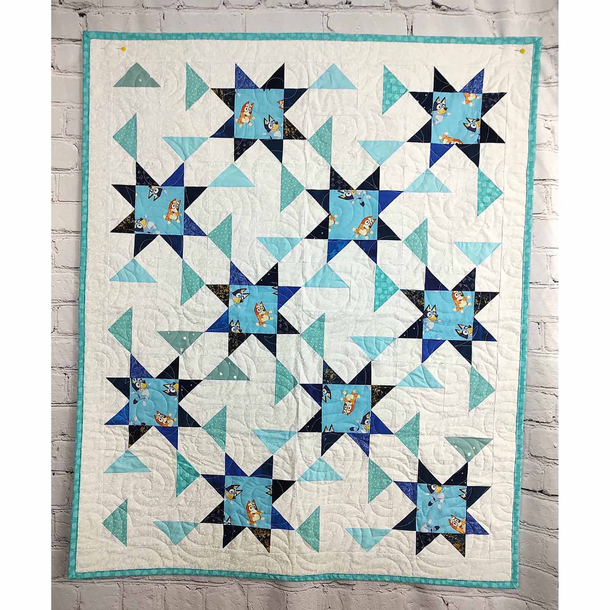 A blue and white quilt featuring a star pattern. This one includes Bluey print in the middle of the stars.