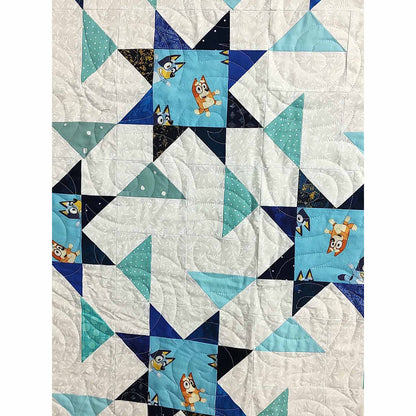 Zoomed into blue and white quilt featuring a star pattern. This one includes Bluey print in the middle of the stars. Close-up so you can see the quilted stitches.