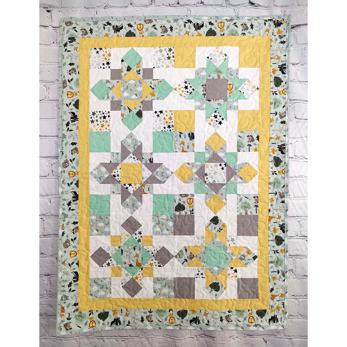 A yellow and gray quilt featuring a green and white design of different stars and 4-patch squares.