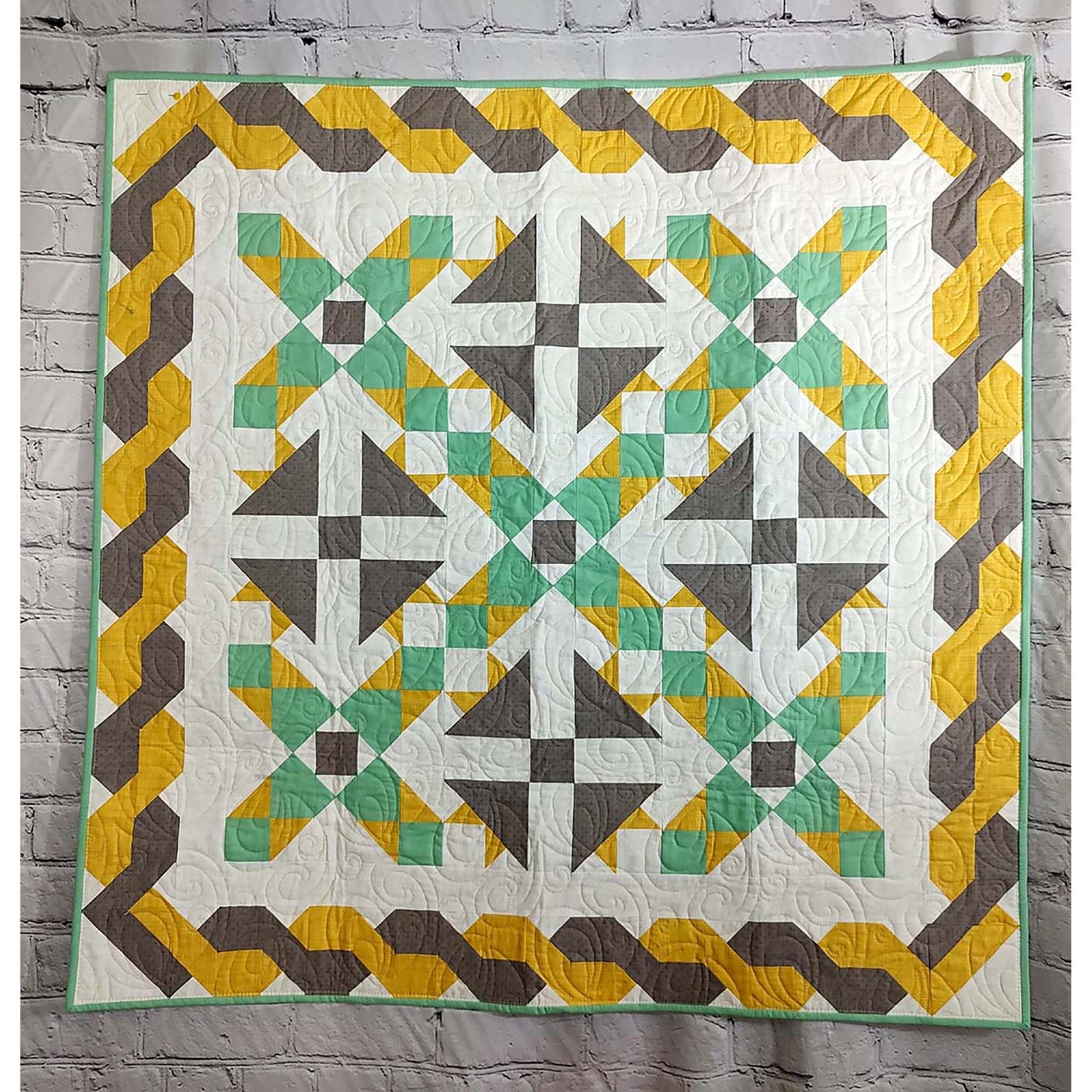 Beautiful quilt in green and yellow with brown accents. Triangle flowers in brown with rows between of green and yellow and braided looking border in brown and yellow.