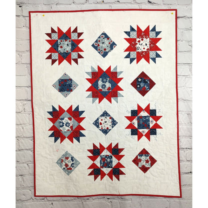 Beautiful quilt features stars and square-in-a-square alternating design in red, white, and blue fabric.