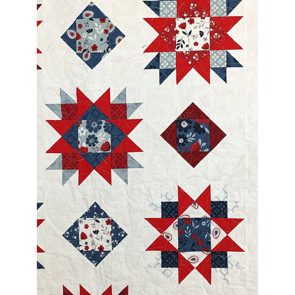 Close up of beautiful quilt features stars and square-in-a-square alternating design in red, white, and blue fabric. Showing the beauty with the quilting added.