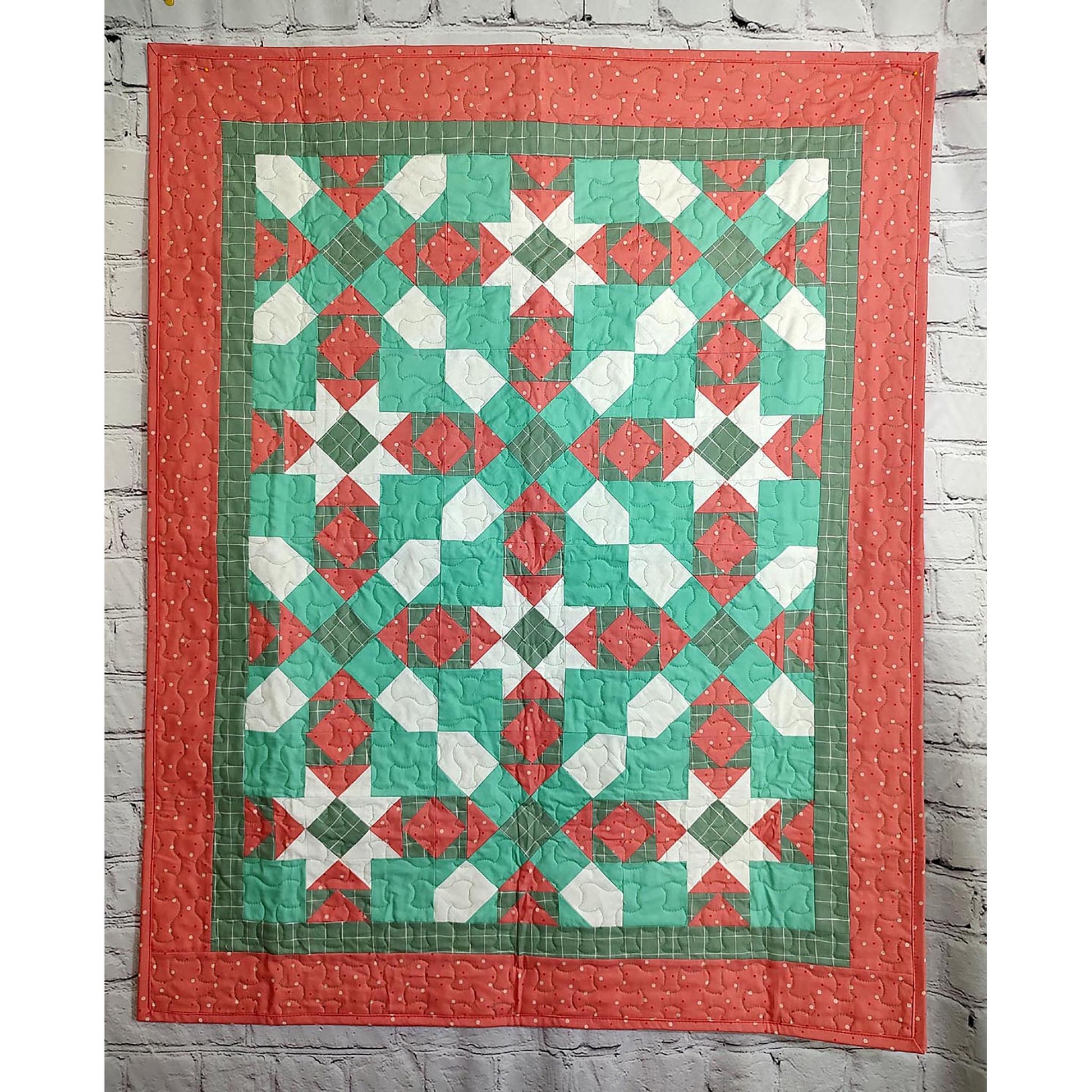 A colorful quilt in red and green, adorned with a continuing star pattern. With the colors, it seems like a Christmas Quilt.