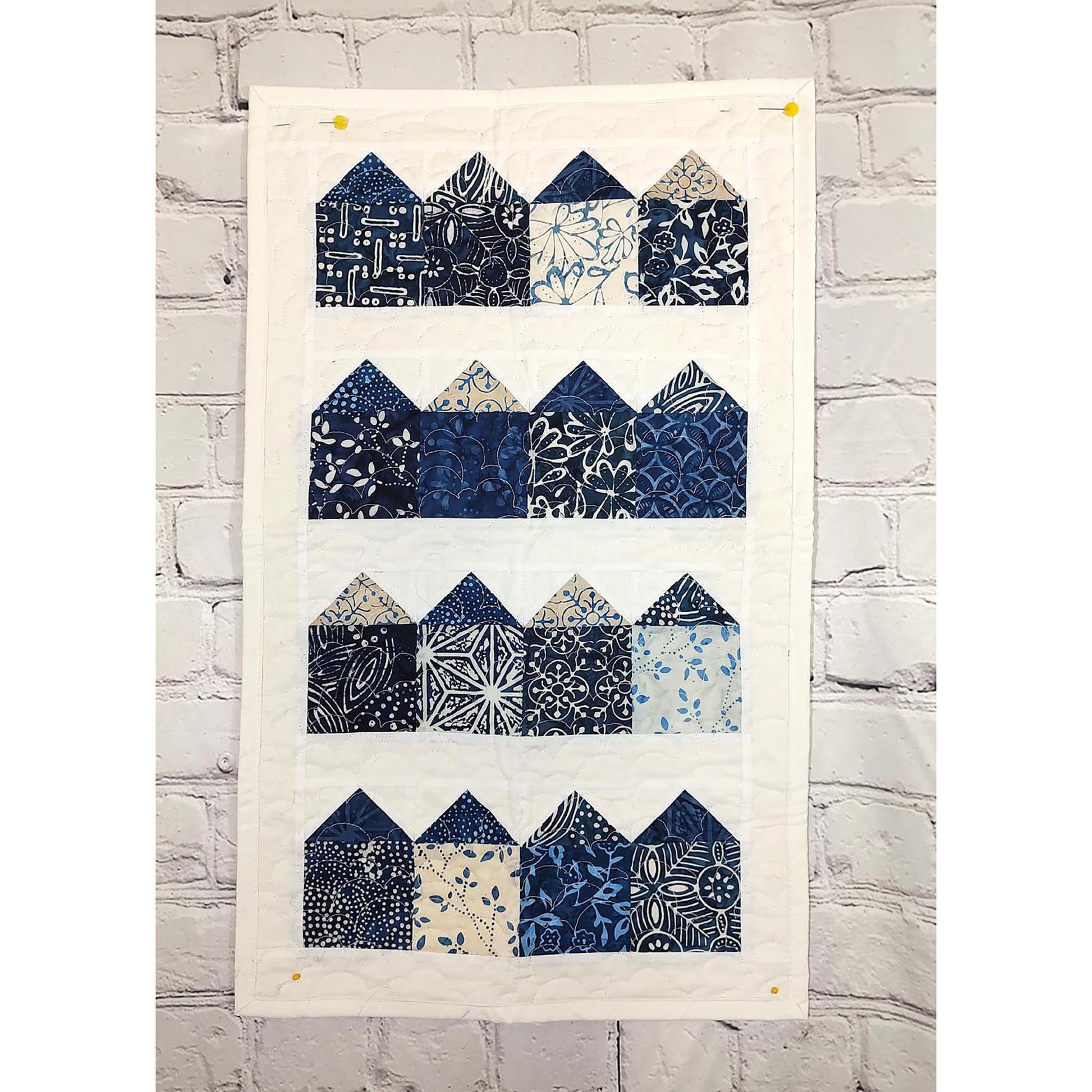 A blue and white quilt featuring charming house designs.