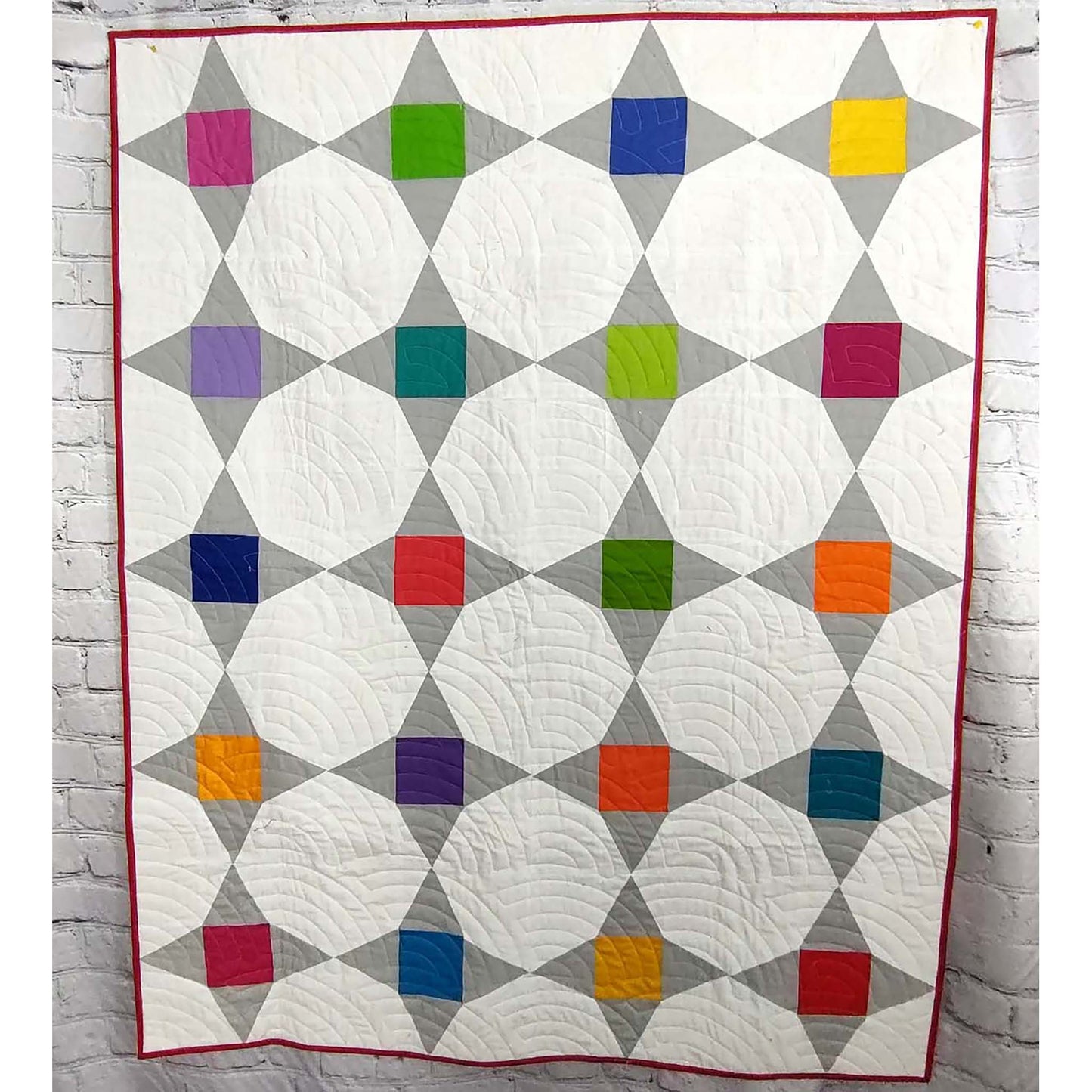 Friendship star quilt features bright colored blocks in the middle of each star with gray as the points and white background fabric.