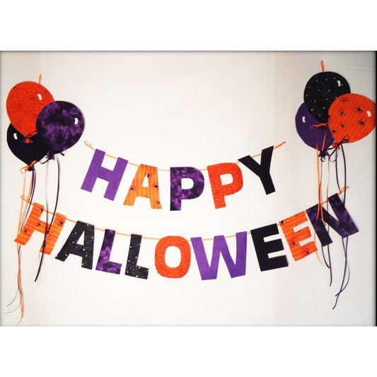 Wall sign hung on the wall with string says "HAPPY HALLOWEEN" and includes balloons.