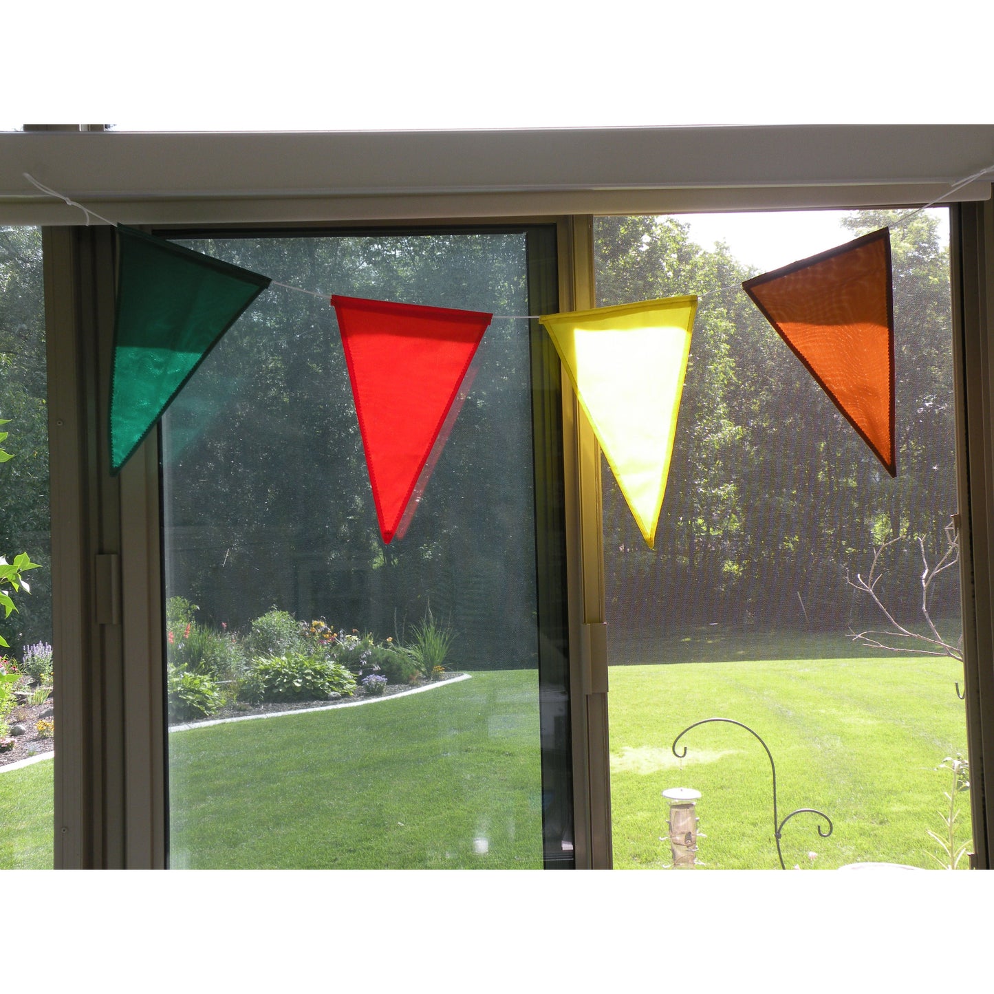 Four colorful pennants showcased in front of a window.