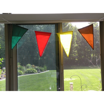Four colorful pennants showcased in front of a window.