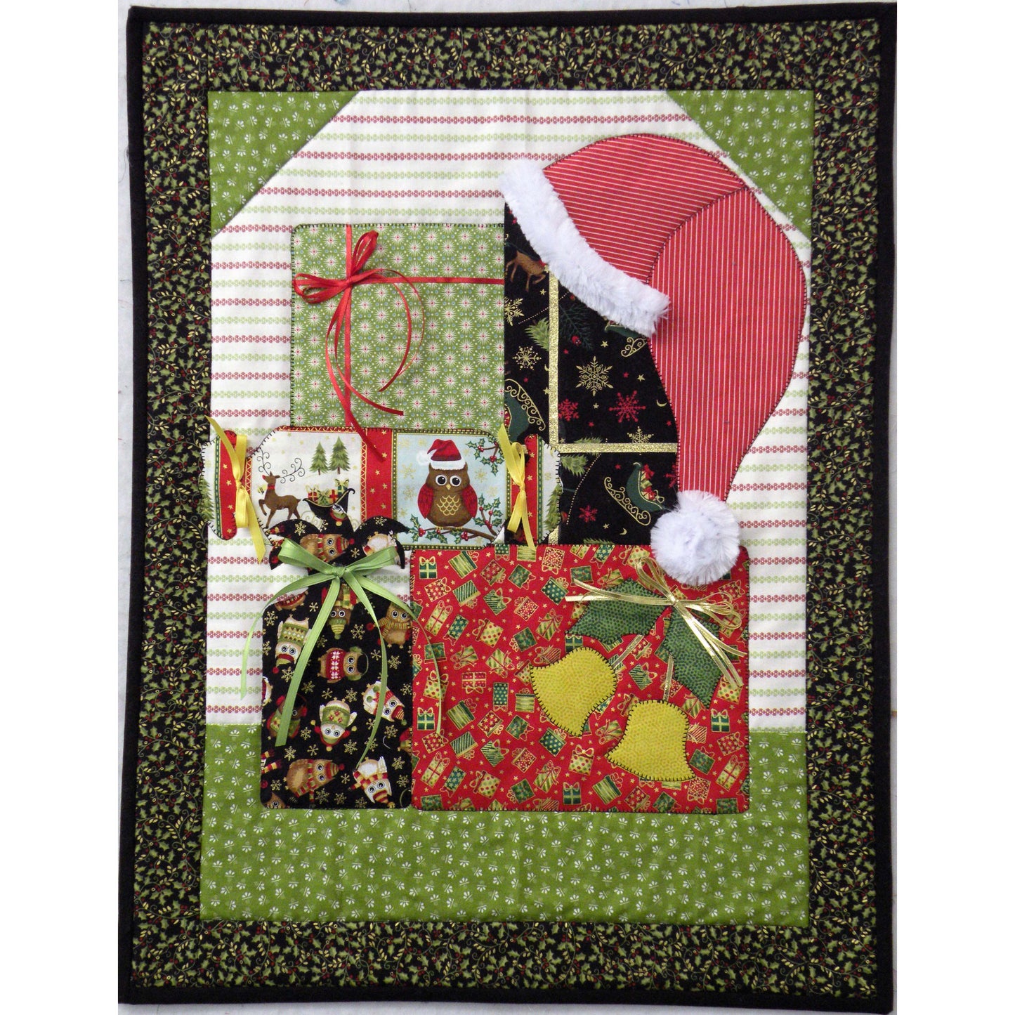 Adorable quilt features a pile of colorfully wrapped gifts with a Santa hat on top.
