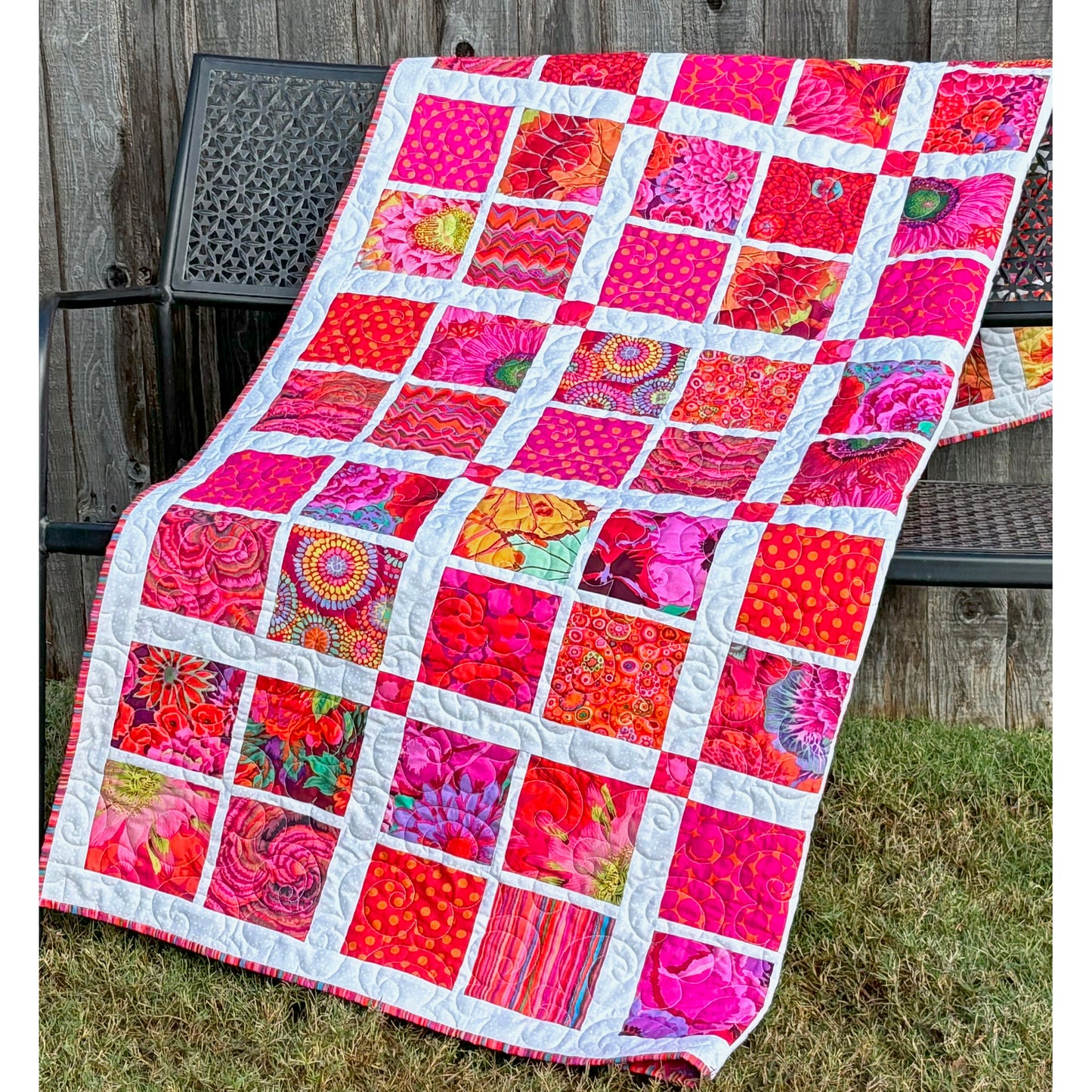 A vibrant pink and orange patchwork quilt showcasing a beautiful blend of colors and patterns.