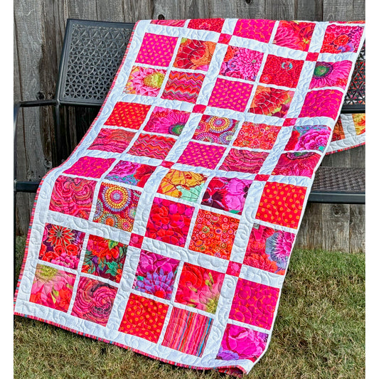 A vibrant pink and orange patchwork quilt showcasing a beautiful blend of colors and patterns.