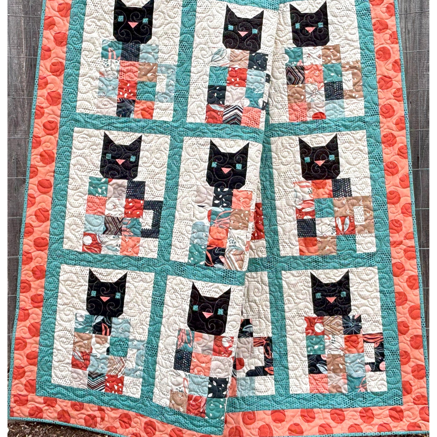 Quilt with black cat heads popping out of patchwork coffee mugs. Perfect for all the coffee and cat lovers in your life.