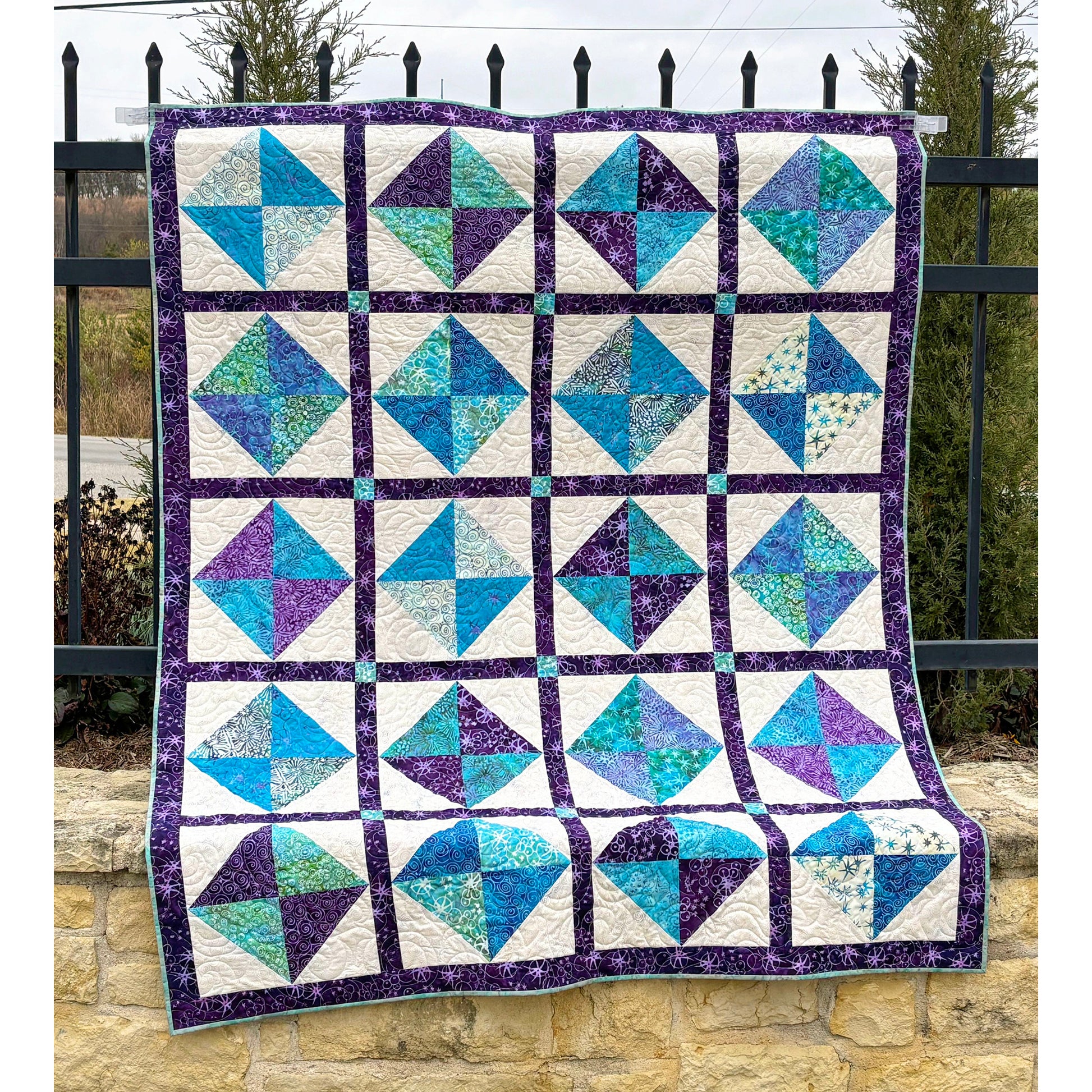 Beautiful quilt features squares of two colors in an hourglass design inside cream squares with darker border to help it all pop.