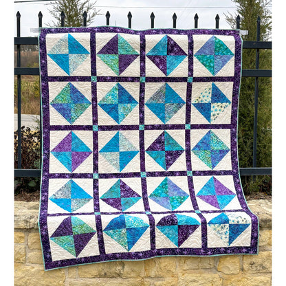Beautiful quilt features squares of two colors in an hourglass design inside cream squares with darker border to help it all pop.