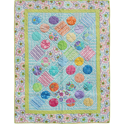 Colorful quilt with circular patterns and floral border on a white background