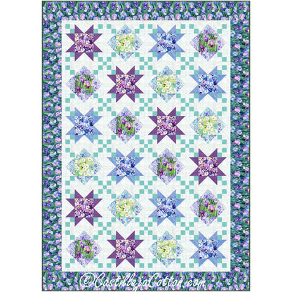 Vibrant quilt in floral purple, blue, green, and cream features a diamond and ohio star pattern with smaller diamonds crisscrossing between these elements. Lovely flower border completes the look.