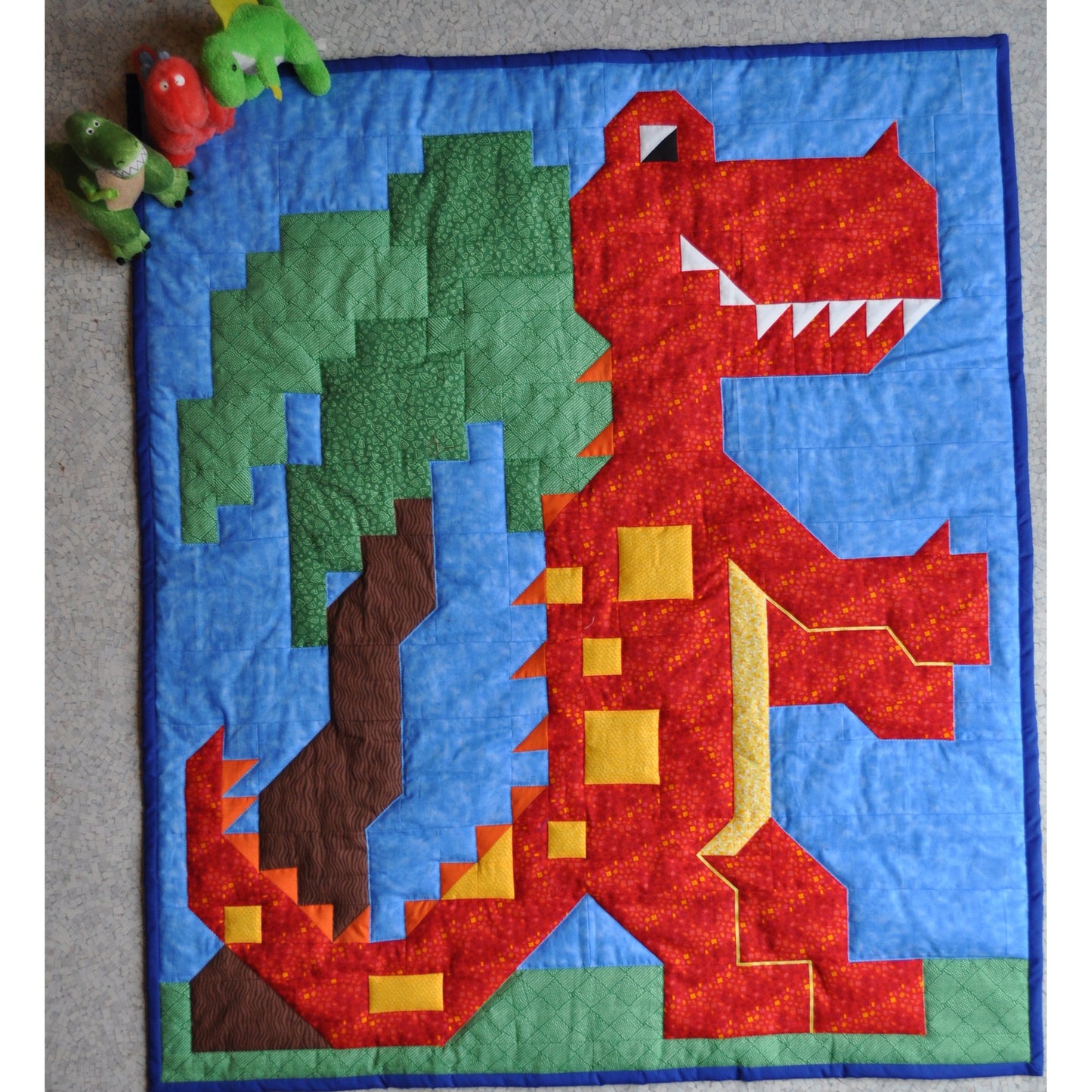Dinosaur/T-rex quilt features a happy dinosaur and a tree.