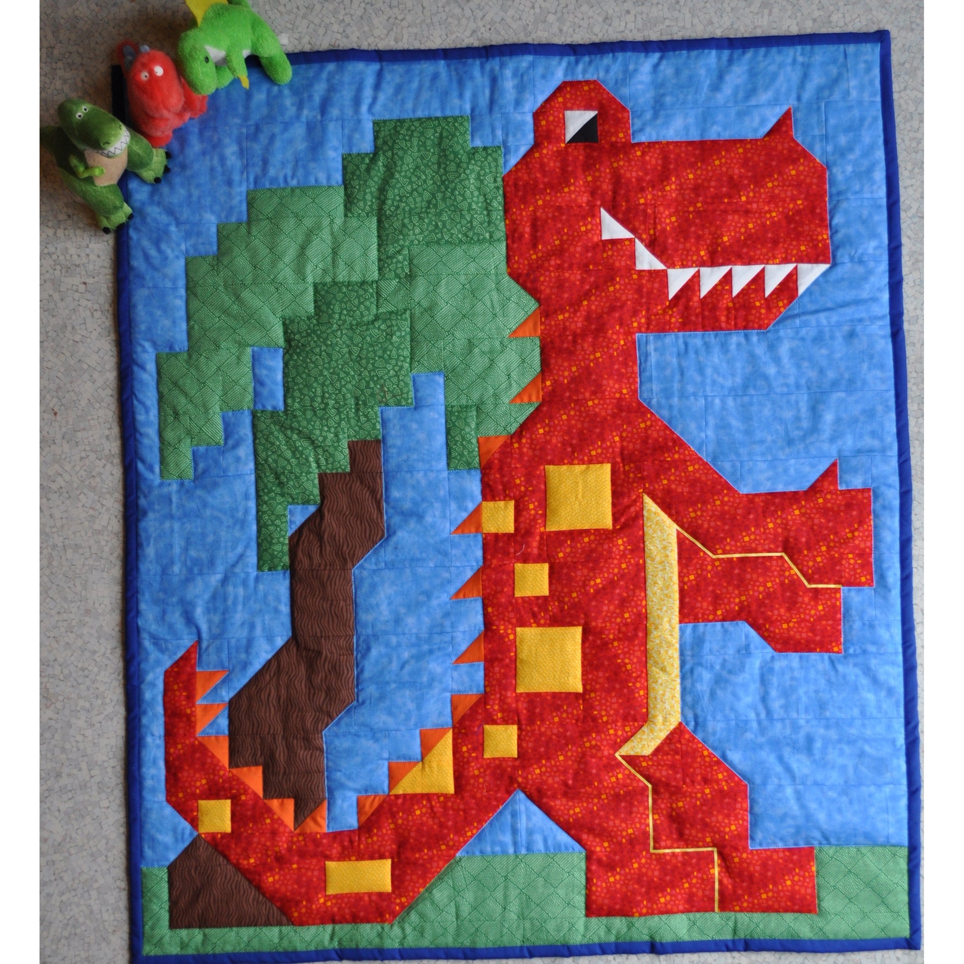 Dinosaur/T-rex quilt features a happy dinosaur and a tree.