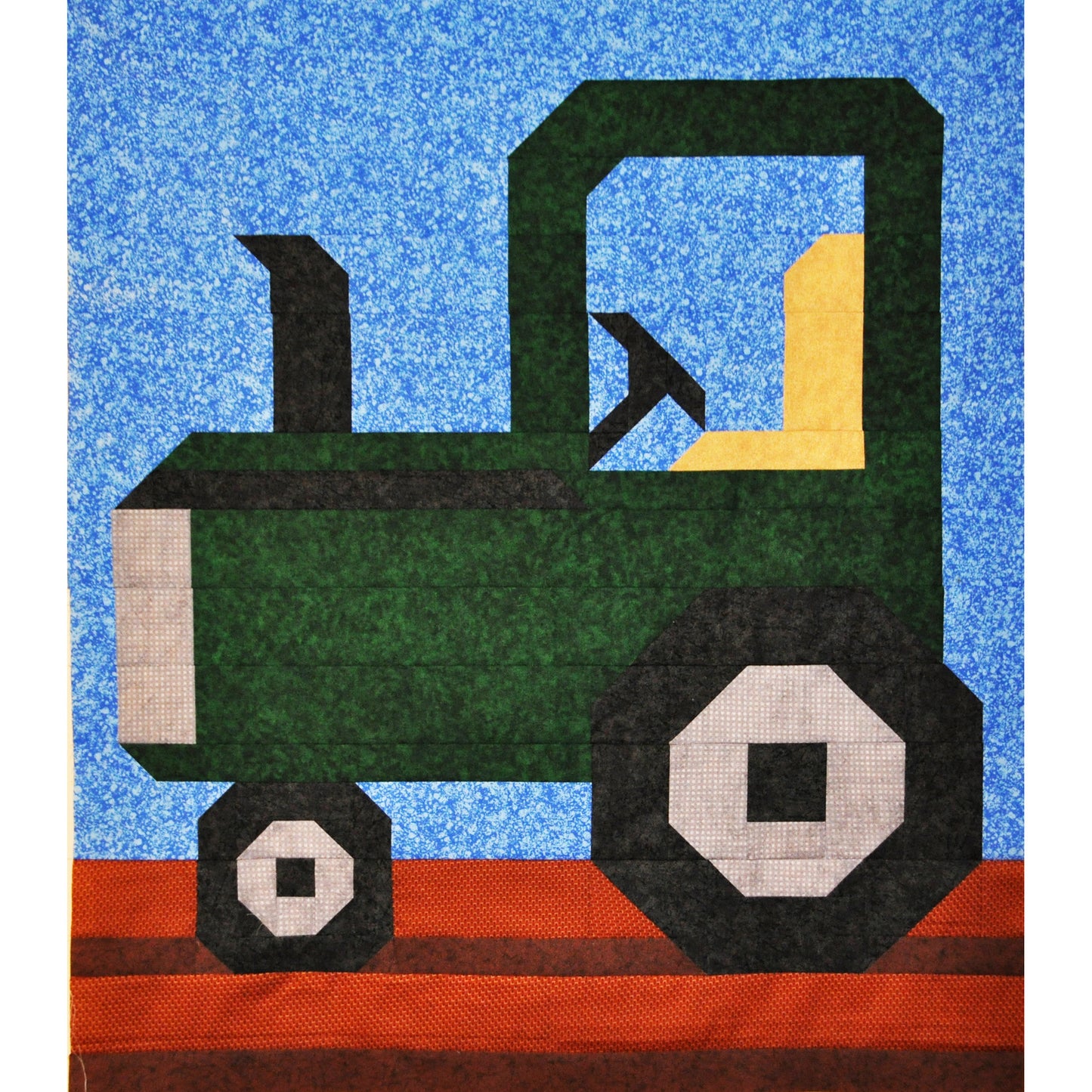Quilt block of a green tractor on a blue background