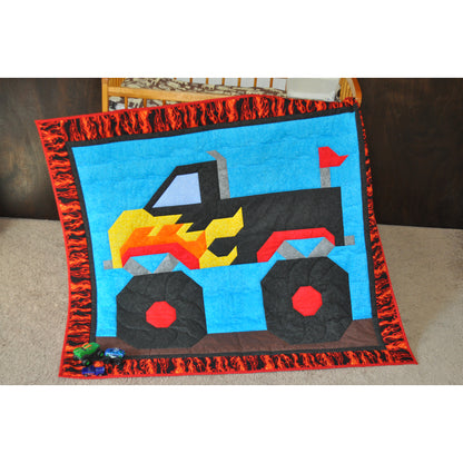 Children's quilt with a colorful monster truck design on a plain background
