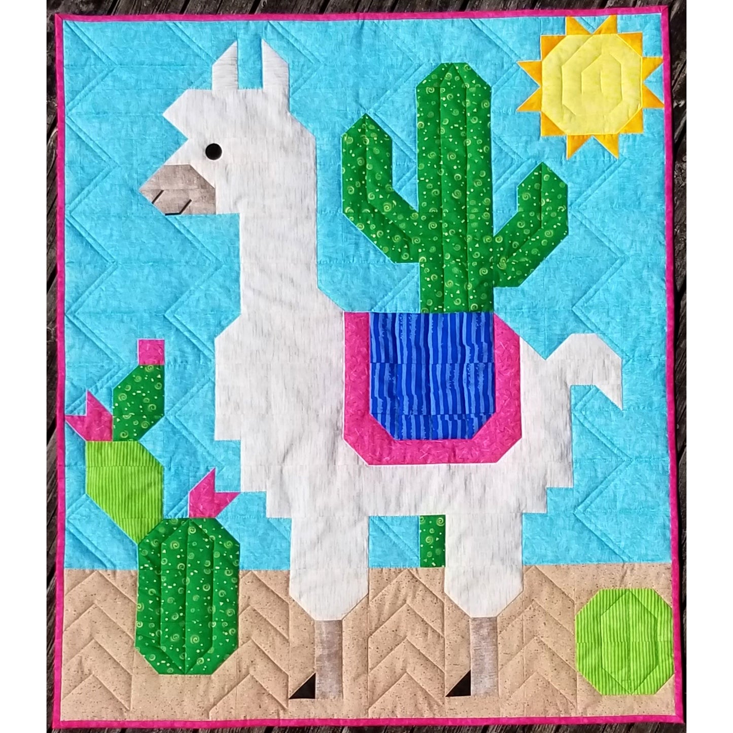 Quilt with llama and cactus design on a blue background