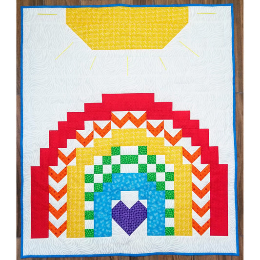 Rainbow quilt features a sun on the top with a pretty rainbow below. Each rainbow color has a different pattern from solid to V or blocks. The middle violet is in the shape of a heart.